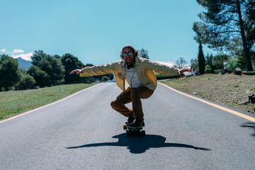 Fototapeta na wymiar Young man skating down the street with his skateboard smiling.