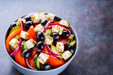 Classic Greek salad with feta and olives on a dark background. Diet and healthy mediterranean salad. Copy space. Top view