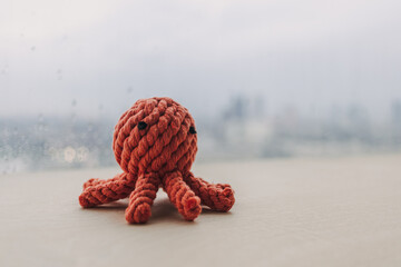 Cute red octopus handmade toy knitting doll on wooden desk with copy space.