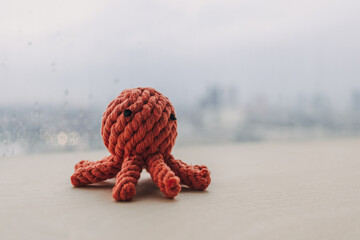 Cute red octopus handmade toy knitting doll on wooden desk with copy space. © Sevendeman