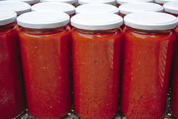 Homemade tomato canning jars. Glass jars with white lid. Inside tomato fry with vegetable ratatouille.