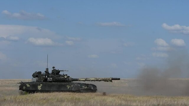 Heavy armored Ukrainian T-80 tank hooting in sand side view. Powerful army technology created for security and defense. Armed military vehicle training to defend people. 4k UHD footage.