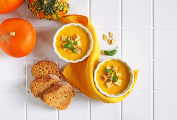 pumpkin soup in bowls with slices of bread and pumpkins, top view