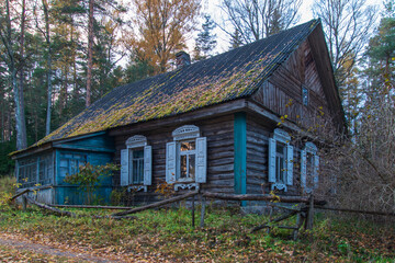 Fototapeta na wymiar An old wooden house with white window shutters in the fall.