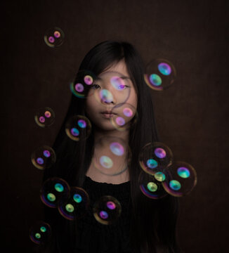fine art studio portrait of asian girl blowing soap bubbles