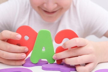 A child, kid holding colorful foam letter A, learning letters and reading concept