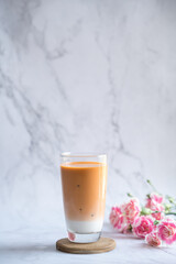 Iced milk tea placed on a coaster with carnations.