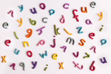 letters of the English alphabet made of multicolored plasticine in a scattered form on a white background
