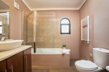 Fototapeta na wymiar Modern traditional bath, with toilet, bathtub, ceramic tiles all around. With drying, towel,