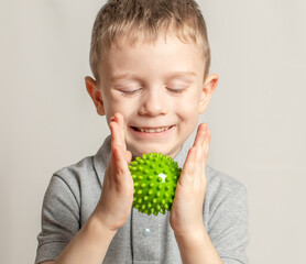 The child performs an exercise with a relief ball the development of tactile sensations. An...