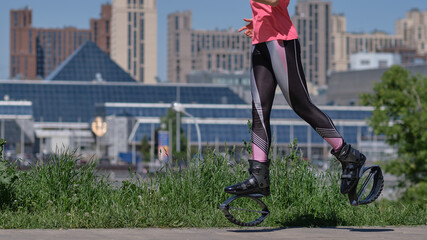 beautiful woman runs along the path in the park, legs in kangoo jumping shoes. women training Kangoo Jumping