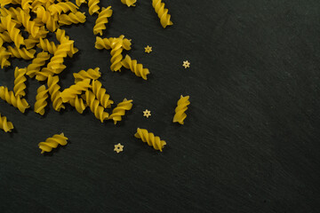 dry paste on a dark background. Paste in the form of spirals. Italian pasta made from fresh raw eggs. Close-up of the ingredients
