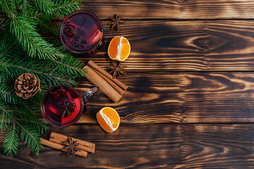 Mulled wine with orange, apple, cinnamon and star anise in transparent glass cups on dark wooden...