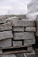 Stack of gray granite slabs on a wooden pallet.  Natural stone packing. The industrial park is under the power lines. Vertical image. 