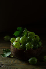 juicy gooseberry berries in a wooden cup on a dark background. High quality photo