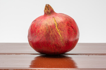 pomegranate with a scar on the skin with a white background on brown tile