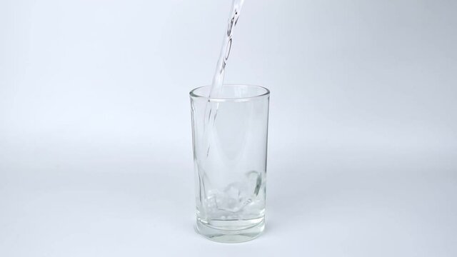 slow motion of pour pure drinking water into a glass with white background.