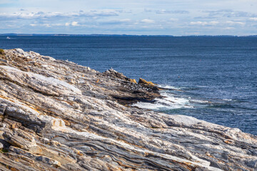 The flag of the United States of America flies patriotic and proud at the Pemaquid Point Lighthouse on the Atlantic Coast of Down East Maine near Bristol.