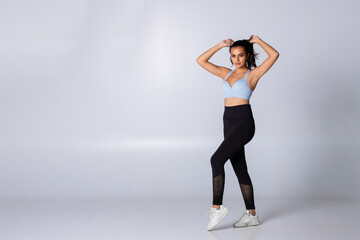 Fit woman standing in sportswear ready for exercise tie her hair on white background, trainer isolated confident and slim