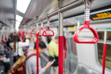 Red hanging handhold for standing passengers in a modern metro train. Suburban and urban transport.