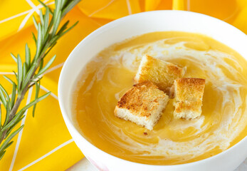 pumpkin soup with cream and crackers in a white plate