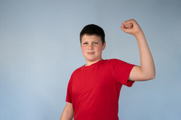 Fun Portrait of Teenage Boy Posing as a Strong Man Flexing Arm on Blue background with copy space