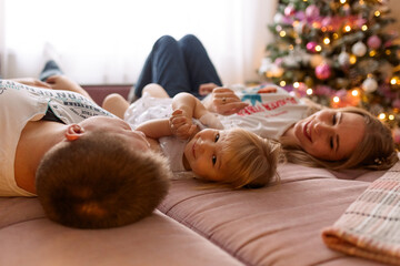 family lying on sofa with christmas tree