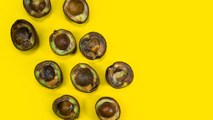 Rotten Avocado halves on Yellow Background. Food Fruits cannot be eaten. Overripe avocado fruit cuts in halfs. Stop wasting food. Unhelthy bad food Concept. Copy Space.