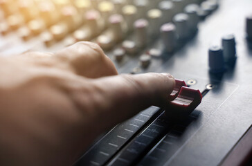The person controls the regulator on the music console.
