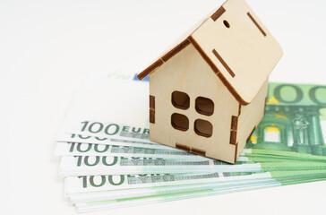 Investments in real estate. On a white background lie the euro and there is a small house.