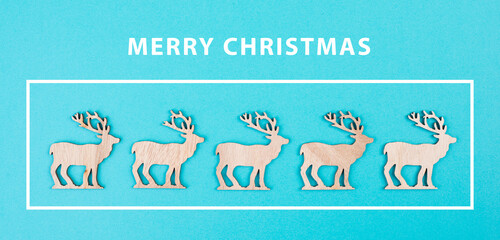 Wooden reindeers in a row on a blue colored background, merry christmas greeting card, wintertime