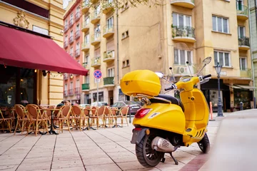 Tuinposter Motor buiten. Gele retro-stijl scooter op de straat van de stad. © luengo_ua