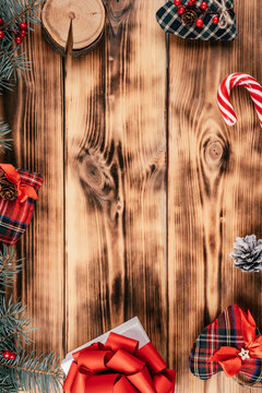 Burnt wood background image with fir branches, gift and Christmas decorations. Top view. Copy space. Vertical