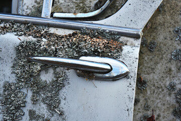 A close up image of a rusted old vintage door handle on a broken car door. 