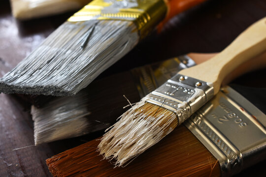 A top view image of several types of old used paint brushes used in home renovations. 