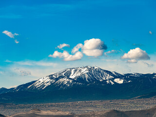 Snow covered Slide Mountain or Mt. Rose, south of Reno, Nevada with a rich blue sky and white puffy clouds.