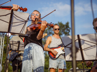 Charming woman violinist playing violin in orchestra