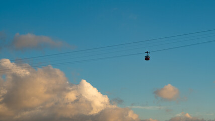 Overhead cable car on sunset. Trolley silhouette. Cloudy sky sunset.