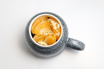 Mug of lobule orange mandarin or tangerine on white background. Creative Christmas hot drink. Holiday mood. Art Christmas concept. Top view