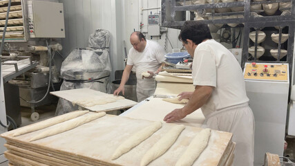 Bakers making doughs and loaves of bread in the factory. several bakers making doughs and loaves of bread in the industry. Concept bread, bakers, industry, factory, artisan.
