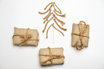 Fototapeta na wymiar Christmas tree made of rope, jute, twine and wooden match on white background. Eco craft gift boxes. Organic DIY eco craft Christmas tree. Creative art holiday. Simple xmas backdrop