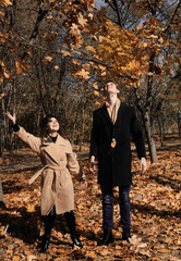 Happy young couple has fun in the autumn park. Young woman and man walking outdoors.