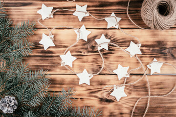 Christmas stars homemade cold porcelain garland with spruce branches on background of burnt wood, top view