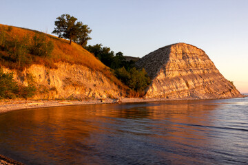 Dawn on the Volga. Beautiful cliffs by the river in the morning rays of the rising sun at golden...