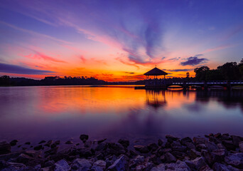 Mesmerizing view of a gazebo over the lake water with trees in the background at sunset