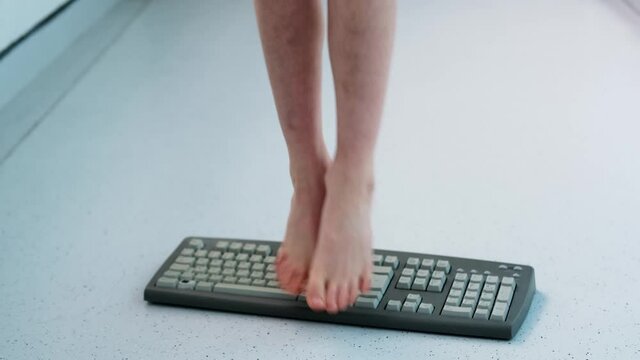 child stands, jumps, dances with his feet on computer keyboard, presses buttons, little vandal, bully plays with gadget, bullying concept, spoils technology until parents can see