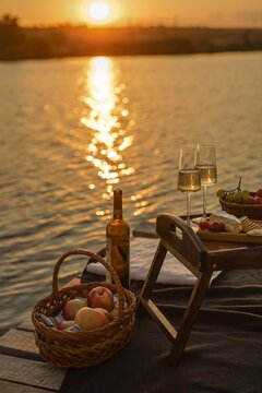 Amazing sunset on the lake, white wine, fruit cake, apples, grapes, brie cheese, biscuits. Autumn aesthetic picnic.