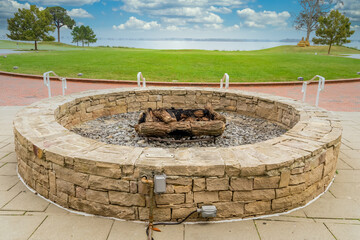 Outdoor patio gas fueled fireplace or firepit covered in stone veneer to roast marshmallows on the...