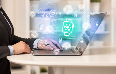 Hands working on laptop with digital icons