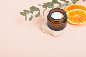 Obraz na płótnie Canvas Background with a jar of face cream, oranges and a branch of eucalyptus with a place for text.